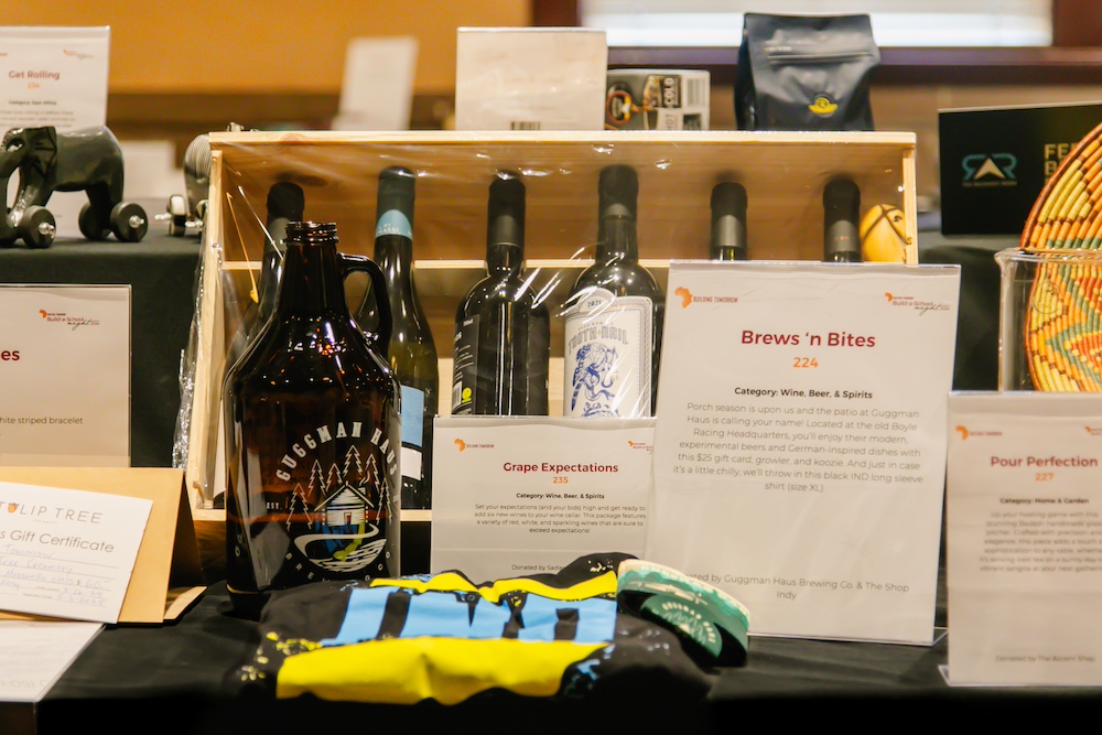 A silent auction item of beer growler and bottles of wine sits on a table